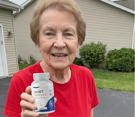 A woman in a red shirt holding a Quiet Nerves bottle outdoors